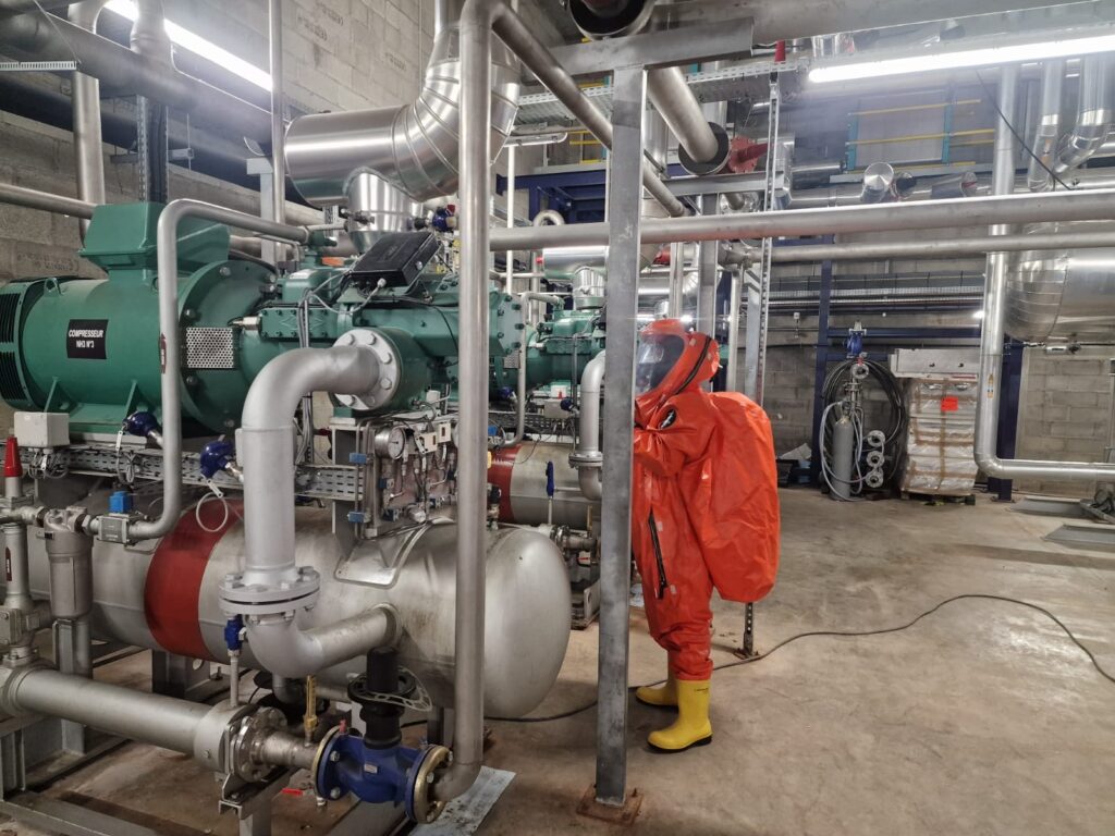 Un technicien en combinaison orange de sécurité travaillant sur une machine de froid